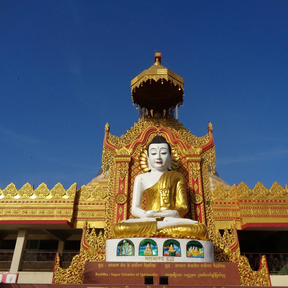 Magnificent golden Buddha statue at a decorated temple entrance in full daylight